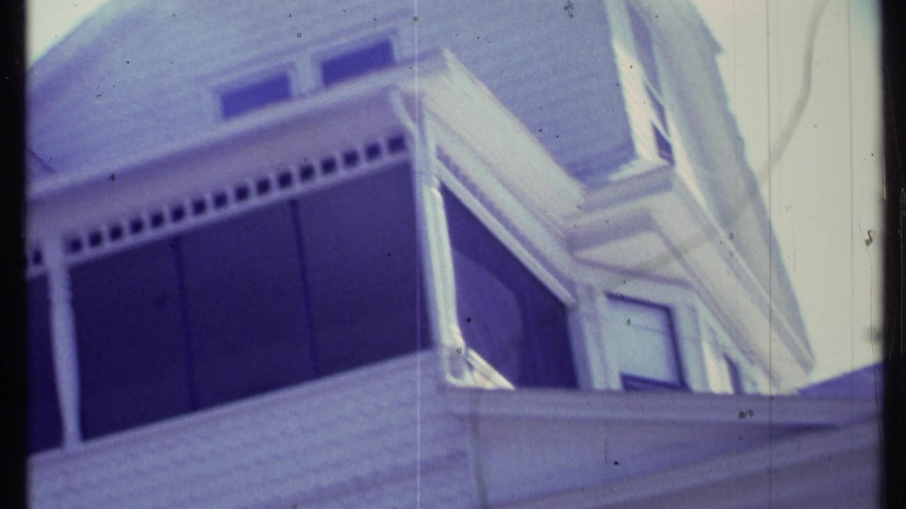 White two-story house seen from below with porch and upper windows.