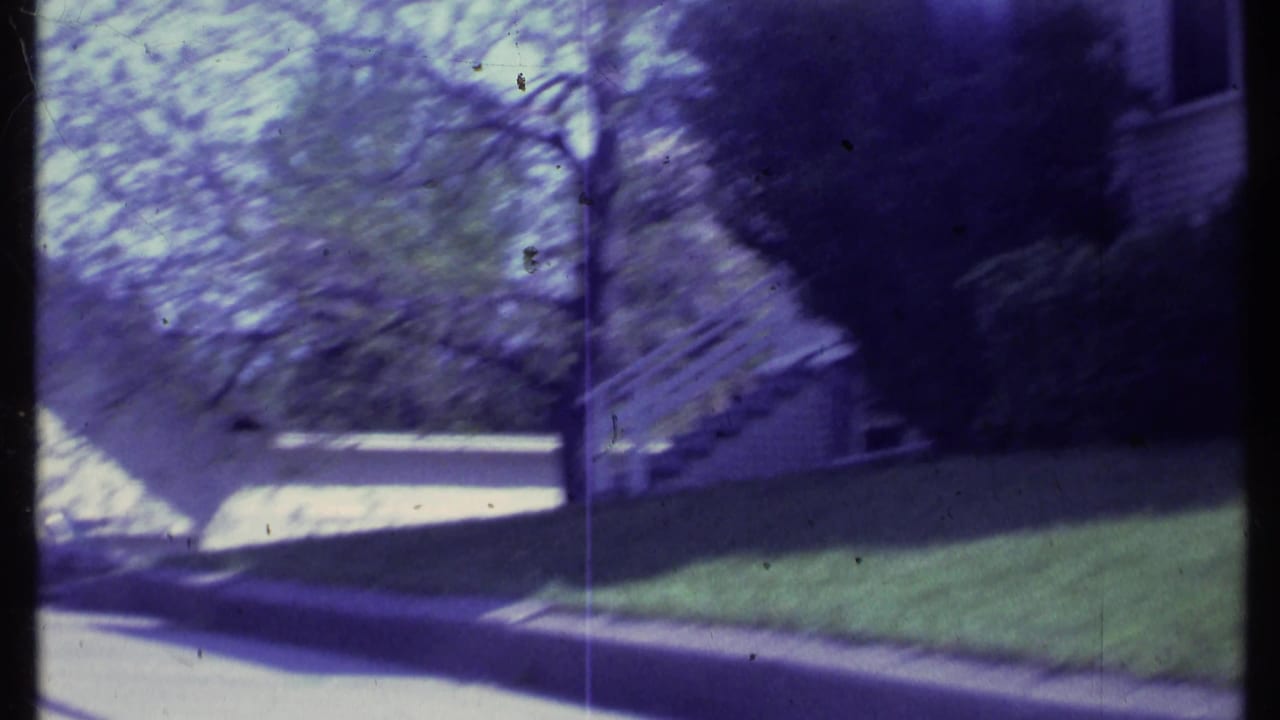 1984 Vermont 8mm frame showing a soft, handheld view of a white residential house beside a lawn, sidewalk, steps, and trees.