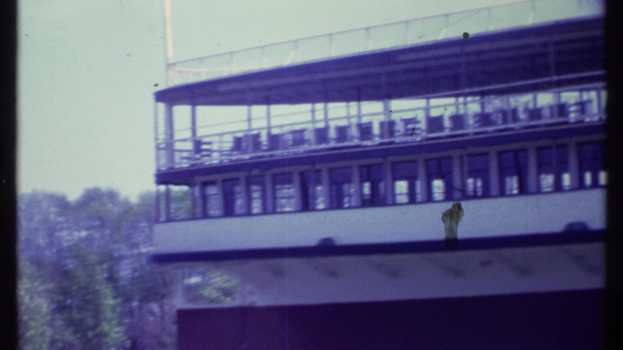 White passenger boat beside trees, with railings and windows visible.
