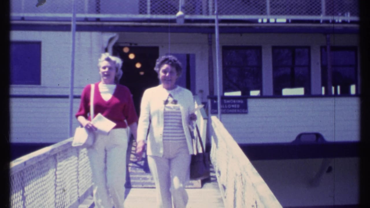 Two women walking down a ramp from a white building in bright sunlight.