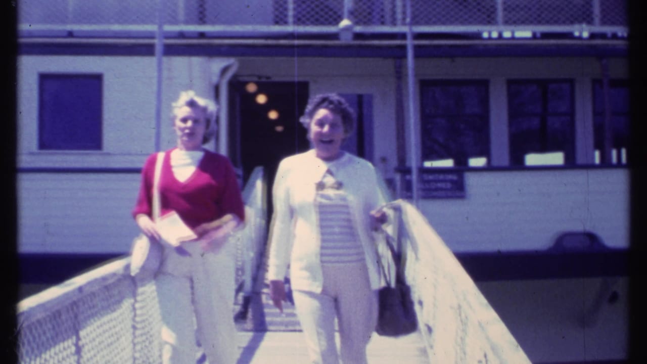 Two women continue walking toward the camera on a railed ramp.