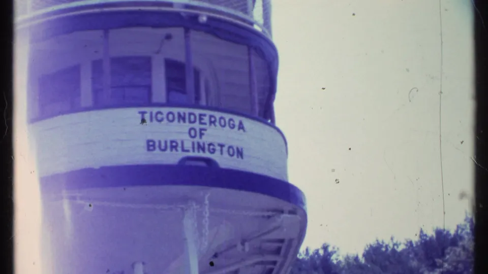 Handheld 8mm view of the Ticonderoga of Burlington name painted on the rounded bow of the vessel.