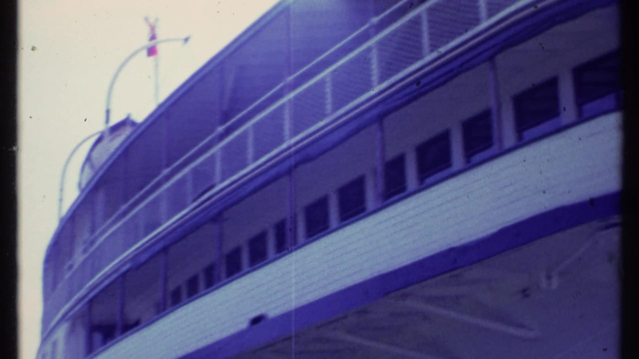 Side of the vessel with rows of windows and curved railings above the hull.