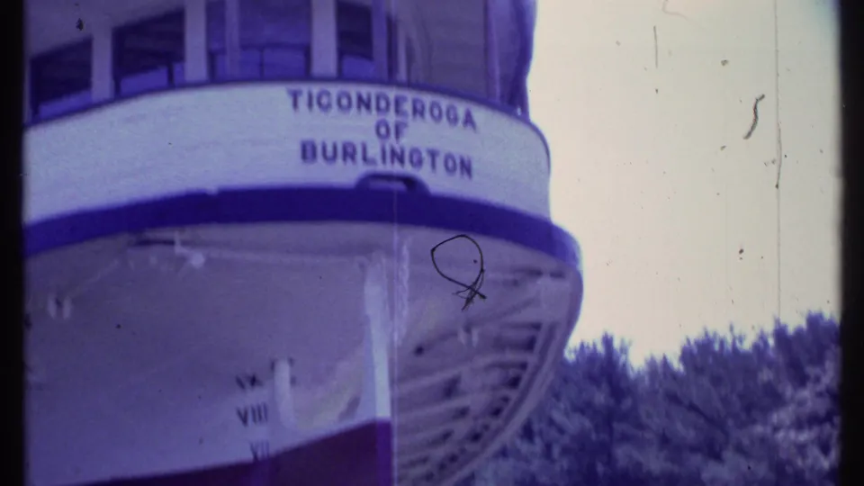 The name TICONDEROGA OF BURLINGTON is visible on the white structure above the vessel's red hull in Vermont footage.