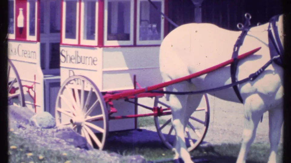 A closer 8mm view shows the white horse, red wagon shafts, spoked wheel, and partial Shellburne lettering on the dairy cart.