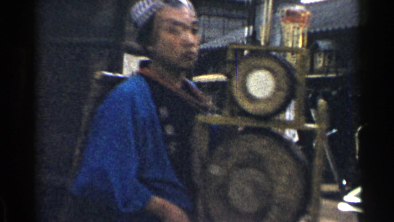Man in blue attire walking beside a display with circular objects and dark film borders.