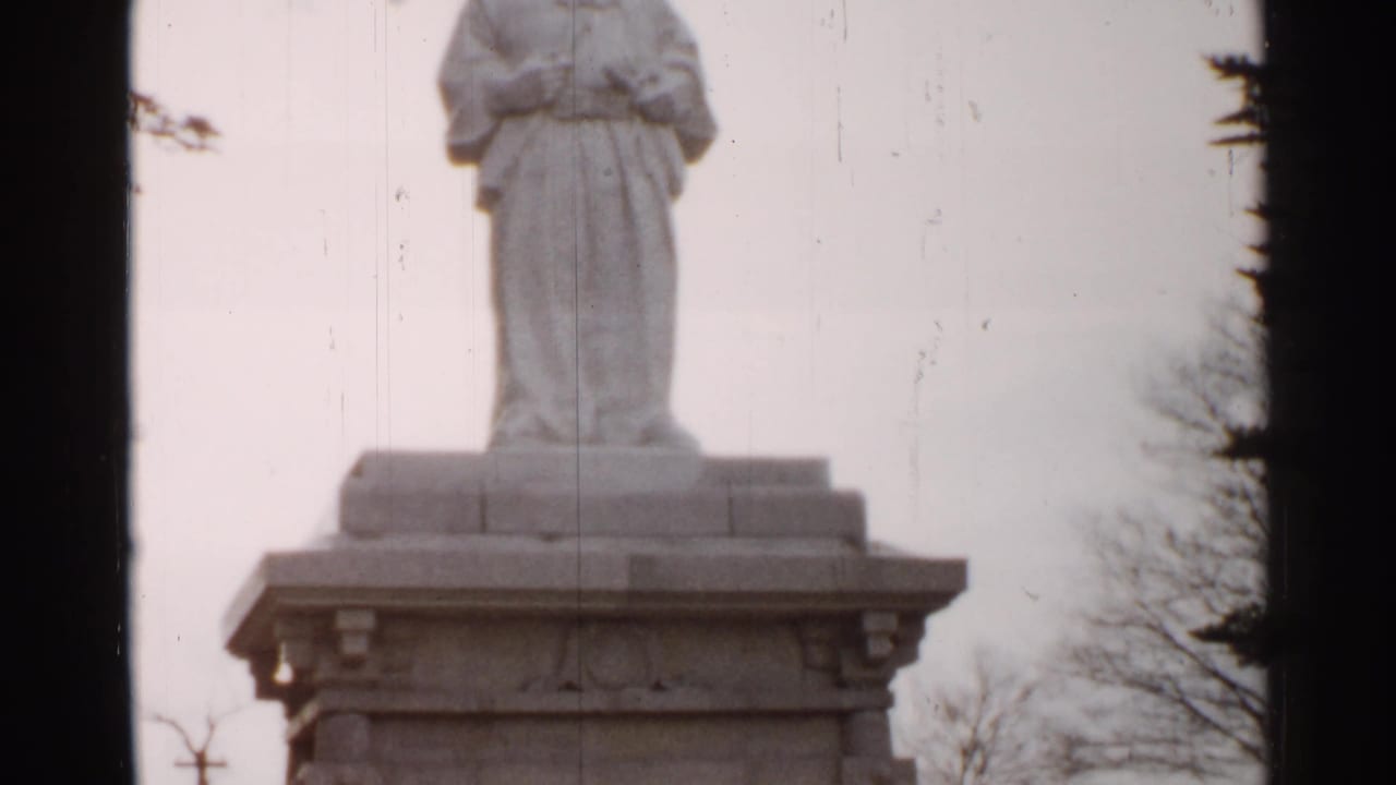 The final frame shows the lower part of the robed stone statue on its pedestal, with trees, pale sky, scratches and 8mm frame edges.