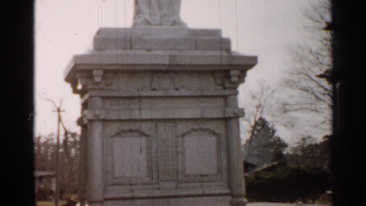 Final frame of the 1952 Japan home movie clip showing the monument pedestal, surrounding trees, and soft cloudy light.
