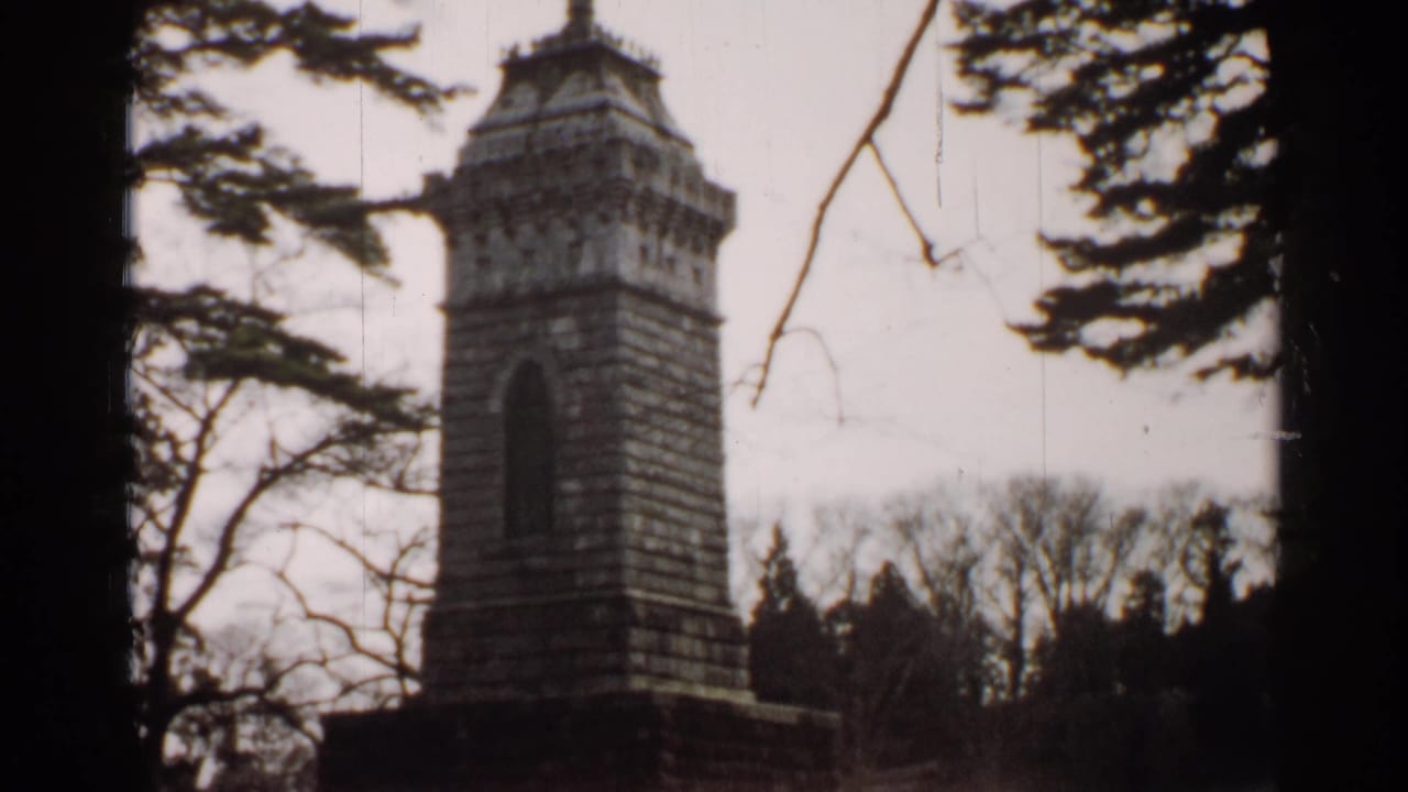 1952 Japan 8mm frame showing the stone monument closer in view, with the bird sculpture partly obscured by branches.