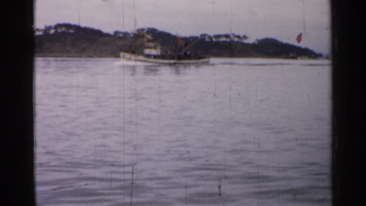 Small boat farther along the water with shoreline in the background.