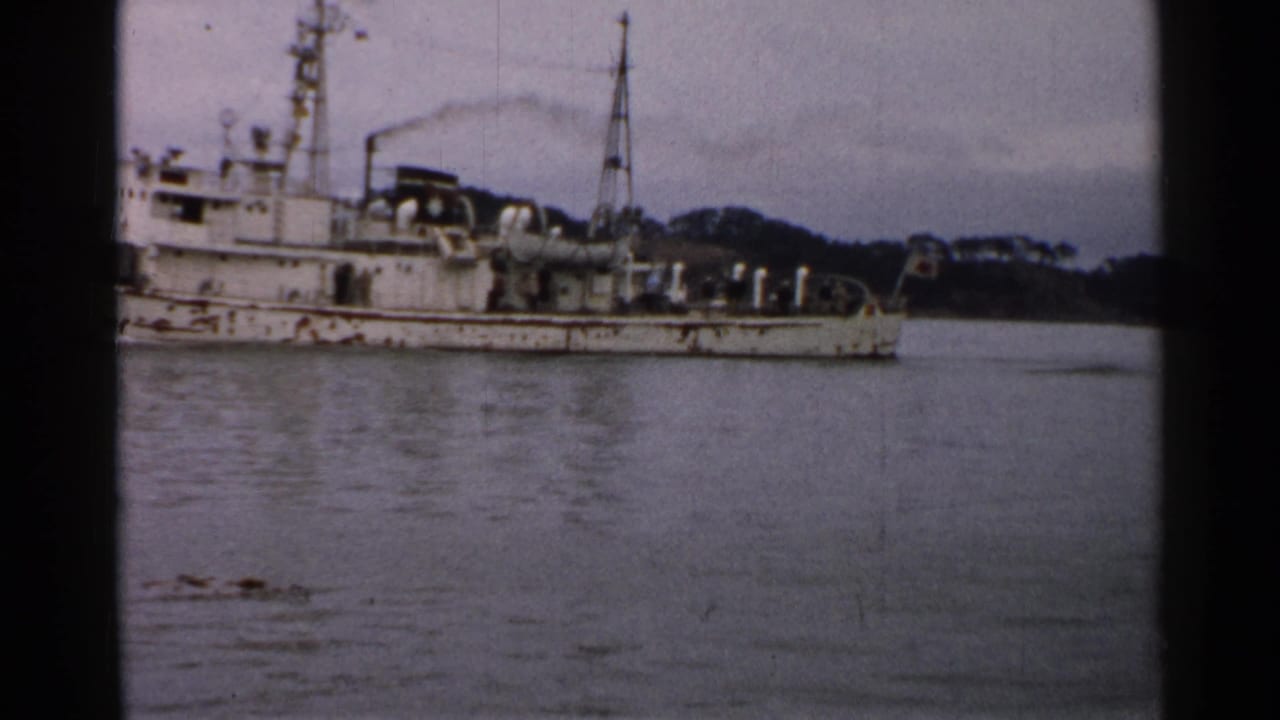 Final 1952 Japan frame showing the weathered PM02 vessel partly cropped, with rigging, deck equipment, calm water, and wooded shore.