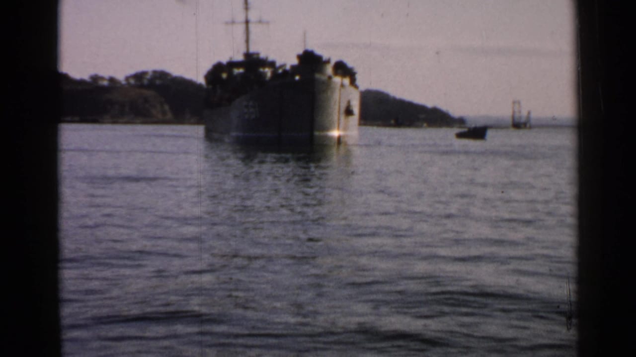 1952 Japan frame showing the large ship on harbor water with a small boat and distant bridge-like structure to the right.