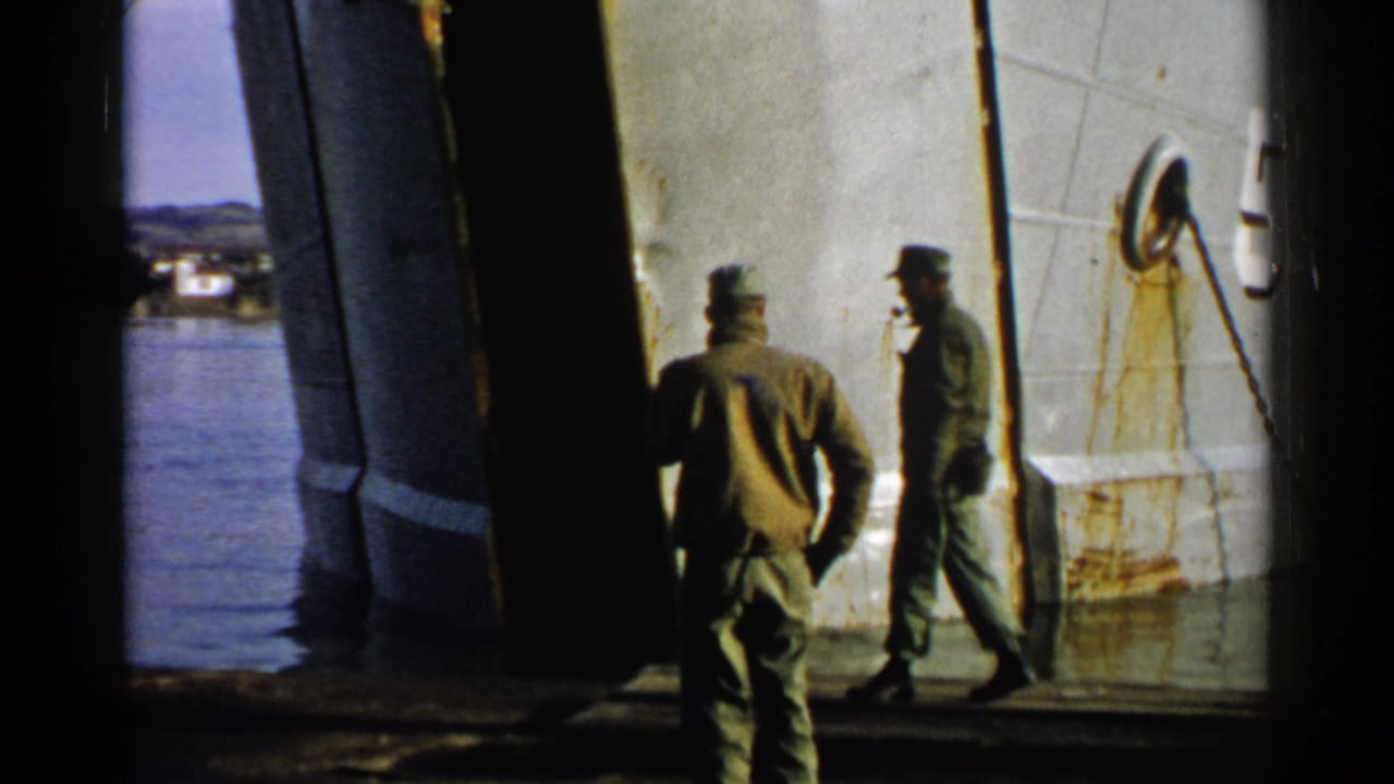 In Japan 1952 home-movie footage, two uniformed men move along a shadowed deck near a white hull and visible water.