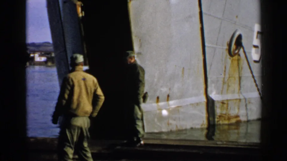 Japan 1952 8mm frame showing uniformed men near a large hull with rust marks and a visible number 5.