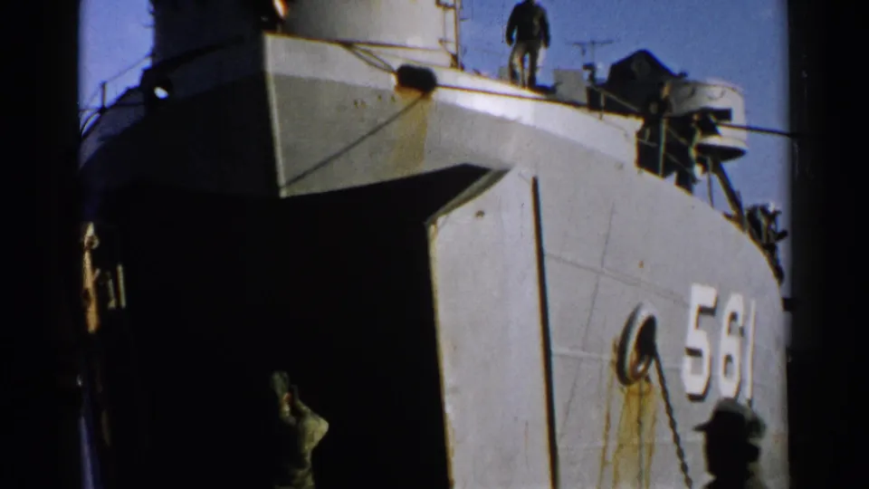 The vessel marked 561 fills the frame as a uniformed guide stands below the open bow, with deck figures and equipment visible above.