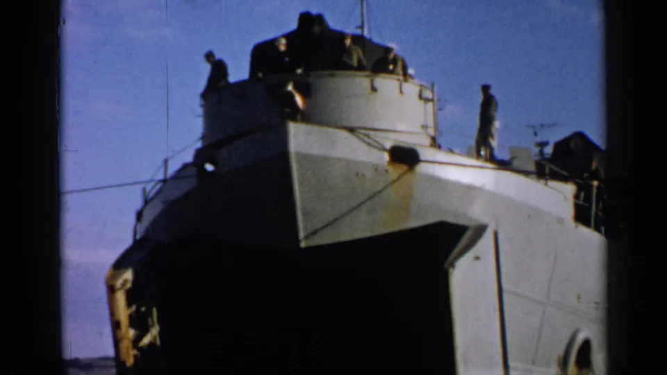 1952 Japan 8mm frame showing a naval-style vessel at port, with crew silhouettes on the upper deck under a clear sky.