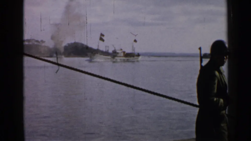 A shipboard view shows a distant boat on a Japanese harbor, smoke on shore, and a dark figure framed at the right edge.