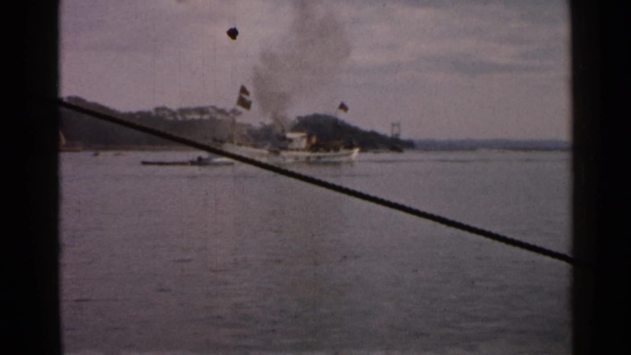 The steam-powered vessel appears farther along the coastal waterway, with hills and a dark cable crossing the 8mm frame.