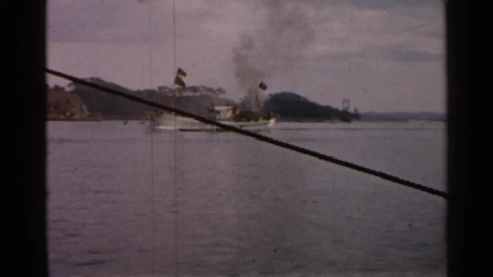 Final 8mm frame of the 1952 Japan coastal vessel shot, with smoke drifting above the boat and a cable cutting across the view.