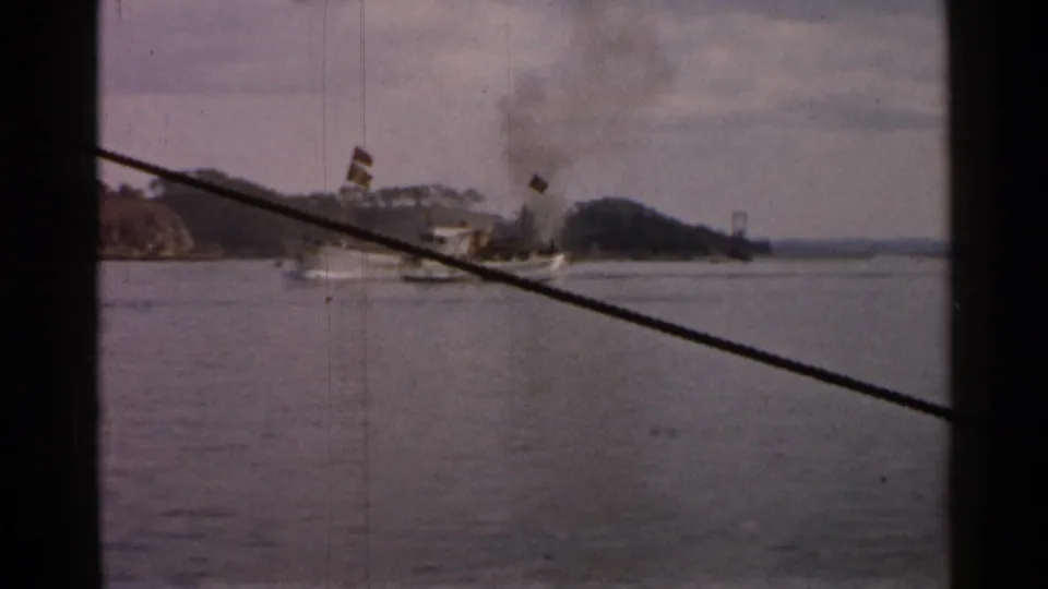 1952 Japan 8mm frame showing a smoking boat on the water, partially obscured by window framing and a diagonal cable.