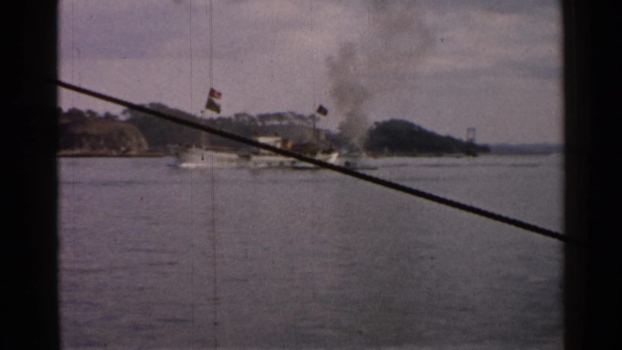 Boat with dark smoke near a shoreline, viewed through a window frame and cable.