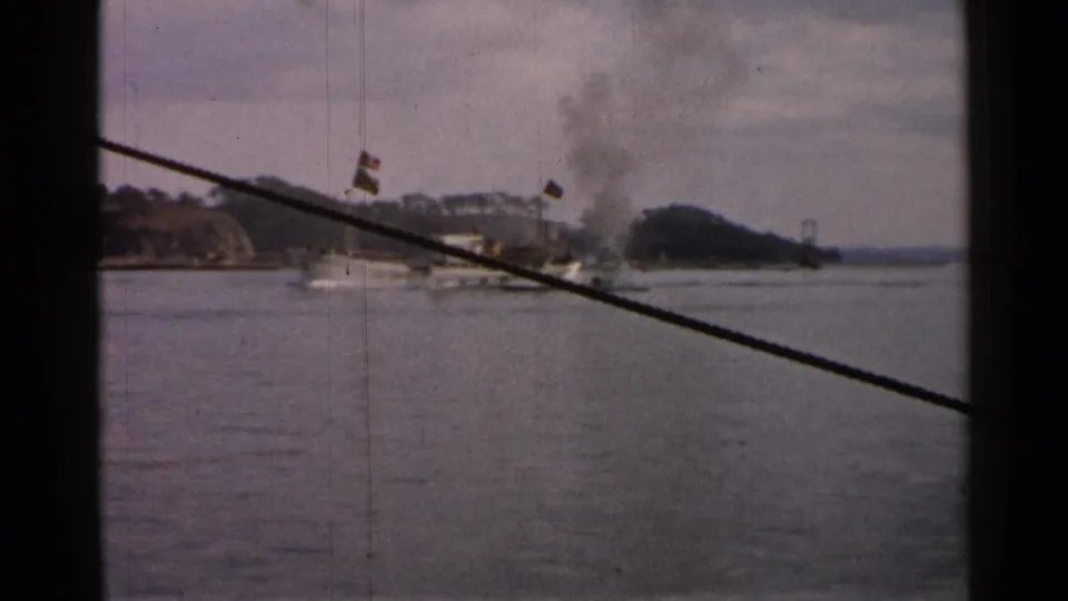 1952 Japan waterfront view of a smoking boat near shore, with dark vertical framing and a diagonal cable in the foreground.