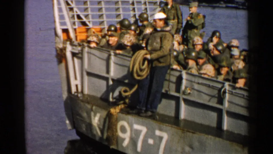 1952 Japan 8mm frame showing soldiers packed aboard a gray ferry marked K-97-7 while a sailor stands near a rope coil.