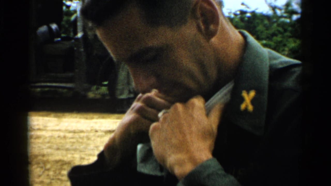 Young U.S. Army soldier looking down while adjusting his uniform collar outdoors.