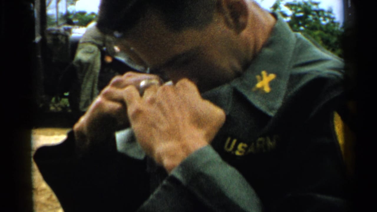 Close view of a soldier bending over his collar with U.S. Army lettering partly visible.