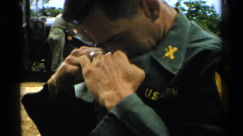 A young U.S. Army soldier in Japan, 1952, bends toward his collar, with partial U.S. Army lettering and insignia visible.