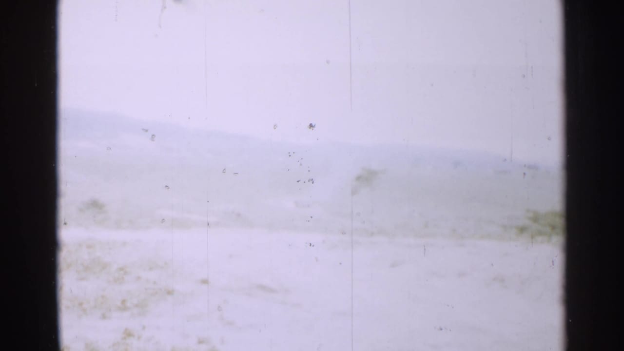 Overexposed snowy or hazy landscape with distant hills and dark 8mm frame borders.