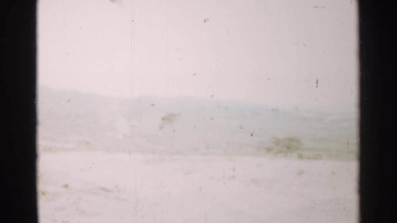 1952 Japan 8mm frame showing a muted snow-covered or hazy landscape, distant ridge line, and light film wear.