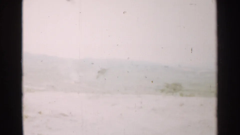1952 Japan 8mm frame showing a muted snow-covered or hazy landscape, distant ridge line, and light film wear.