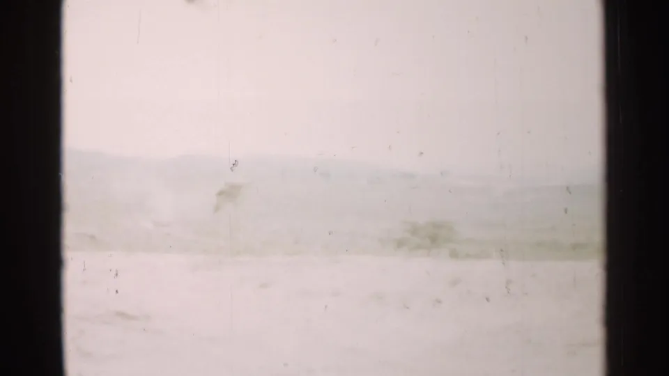 1952 Japan 8mm frame showing a hazy green landscape and distant mountains through a dark window frame.