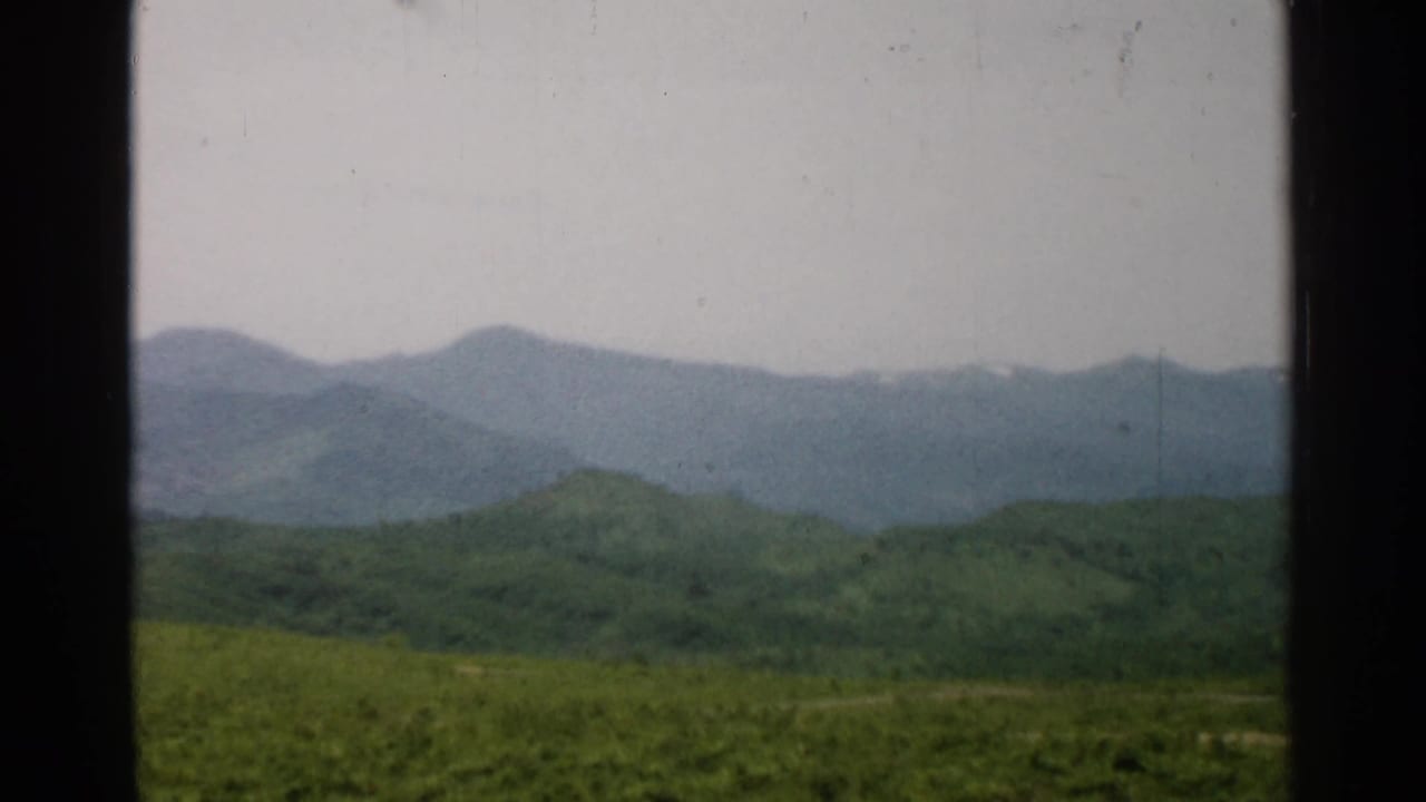 Green hills and blue-gray mountains framed by a window opening.