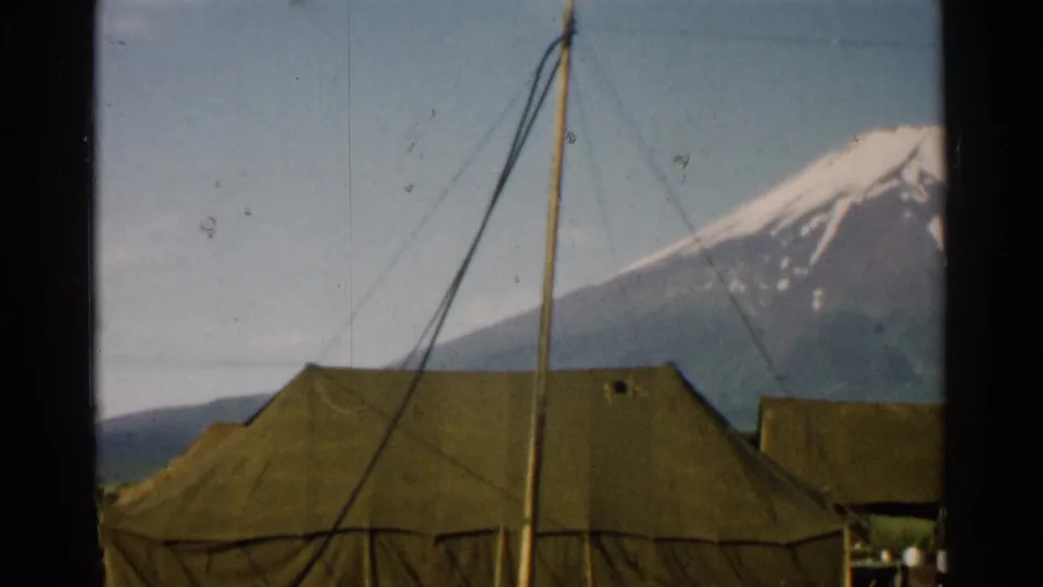 1952 Japan frame with a large olive tent in the foreground, tent rigging, partial figures at the edges, and Mount Fuji behind.