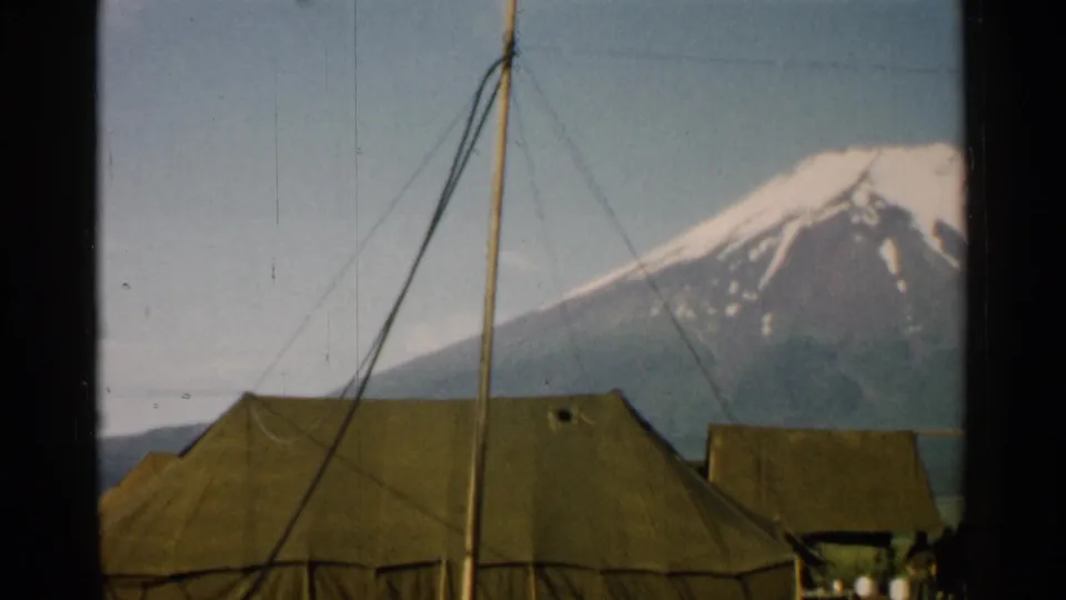 1952 Japan 8mm frame showing a tent roof, crossing support lines, a smaller tent, people at the edge, and Mount Fuji in the background.