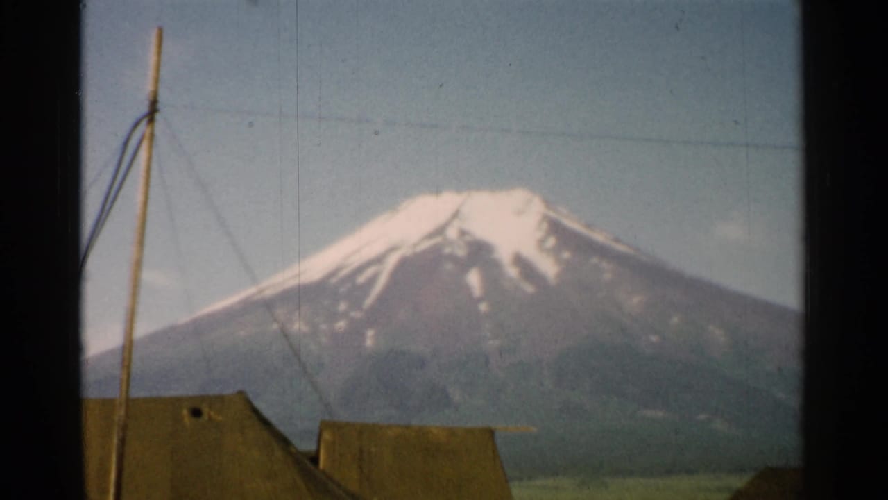 1952 Japan 8mm frame showing Mount Fuji larger in view, with tent tops and a pole cutting across the lower foreground.