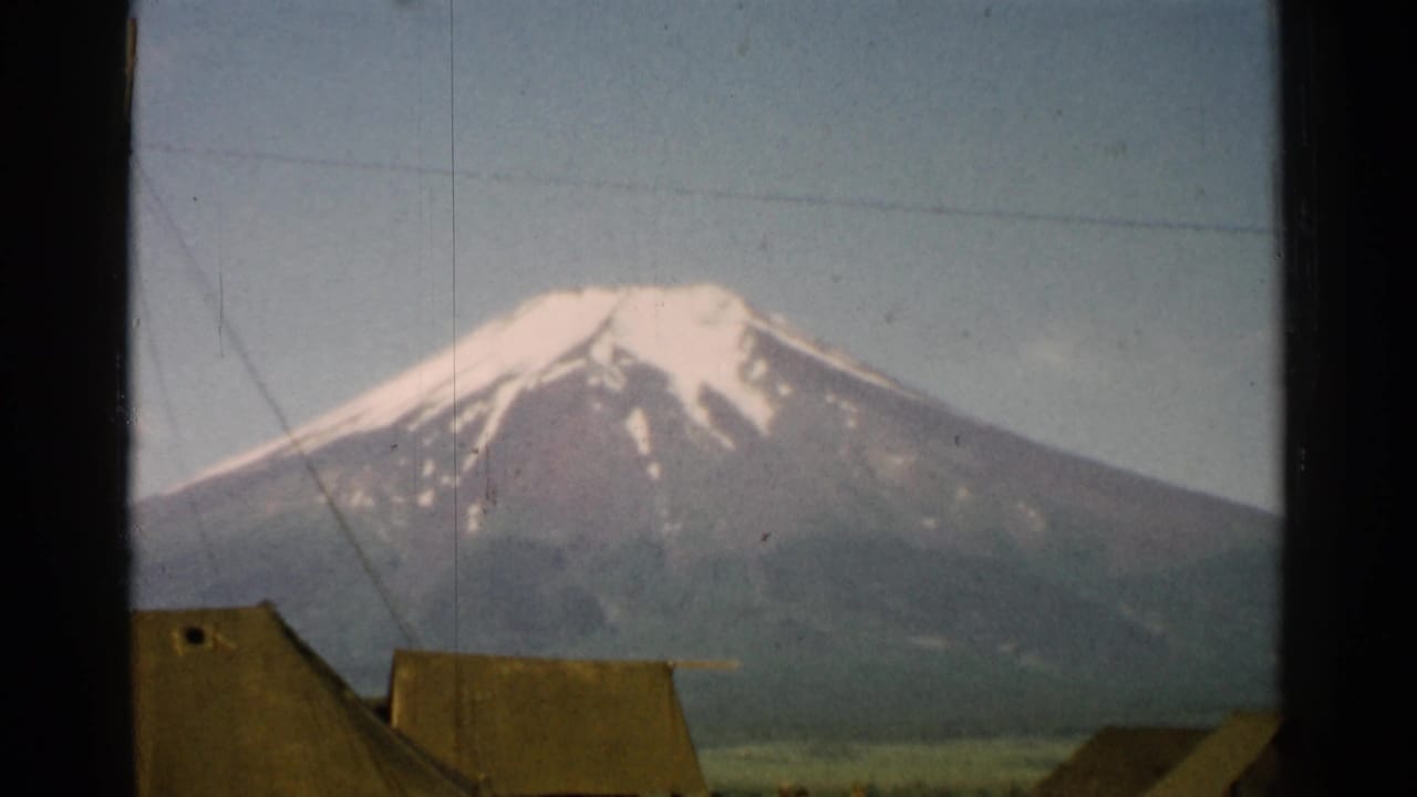 1952 Japan 8mm frame of snow-capped Mount Fuji over low canvas tents and diagonal guy wires, with visible film borders.