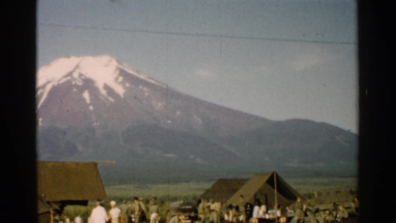 1952 Japan 8mm frame showing a rural village foreground with small people and Mount Fuji rising behind it.