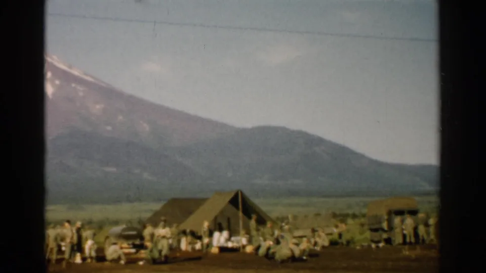 1952 Japan home-movie view of a canvas tent, personnel, and camp equipment below the lower slopes of Mount Fuji.