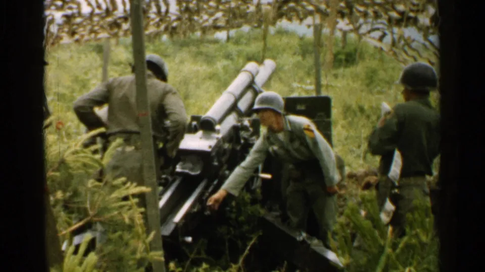 Helmeted soldiers continue preparing or operating a field cannon in a wooded grassy area, consistent with 1952 Japan metadata.