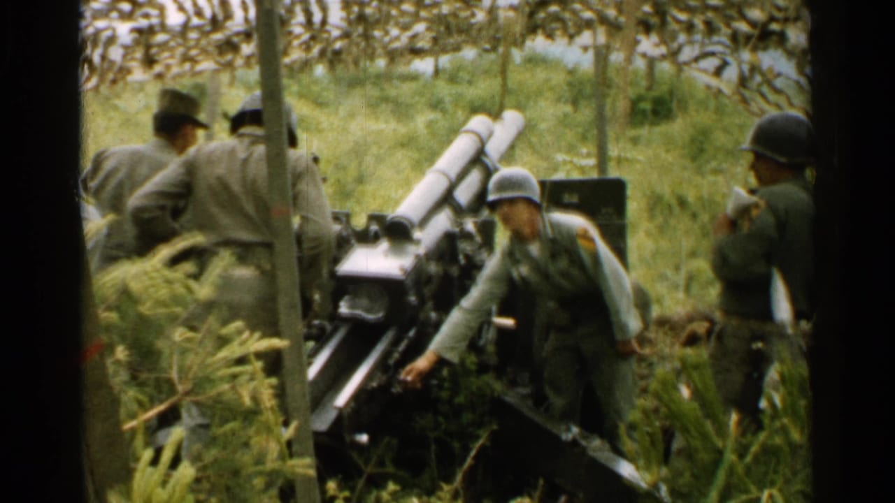 Helmeted soldiers stand around a field artillery cannon in grass and trees.
