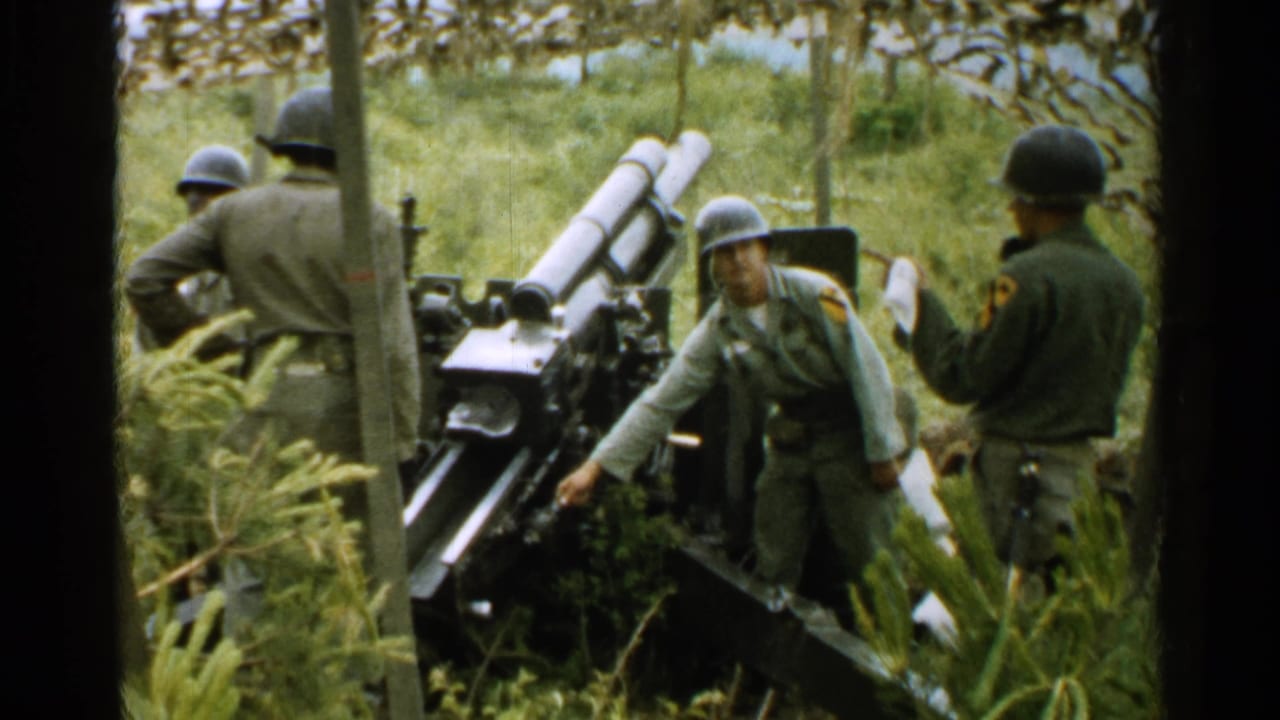 1952 Japan footage shows U.S. soldiers in helmets working beside a field artillery cannon in a wooded green setting.