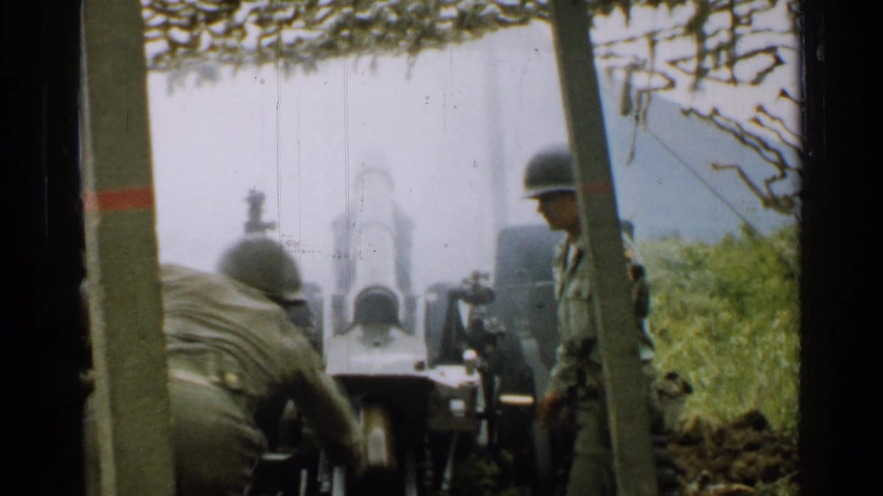 Helmeted soldiers operating an artillery cannon in a wooded field position.