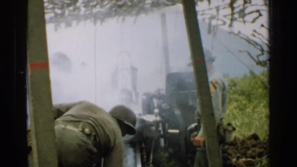1952 Japan 8mm frame with soldiers near a field artillery piece as smoke or haze surrounds the cannon.