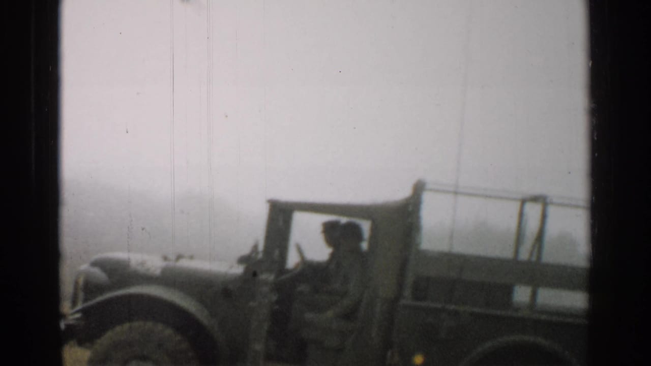 Canvas-top military vehicle seen close beside a road in a Japanese town.