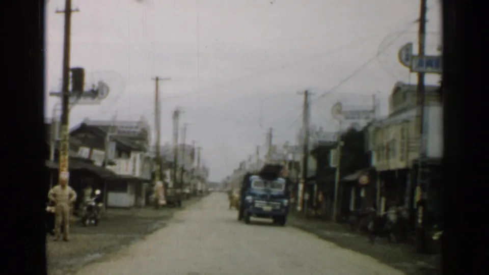 The later 1952 Japan street frame shows a truck coming toward the camera, with pedestrians, low buildings, overhead wires, and visible signage.
