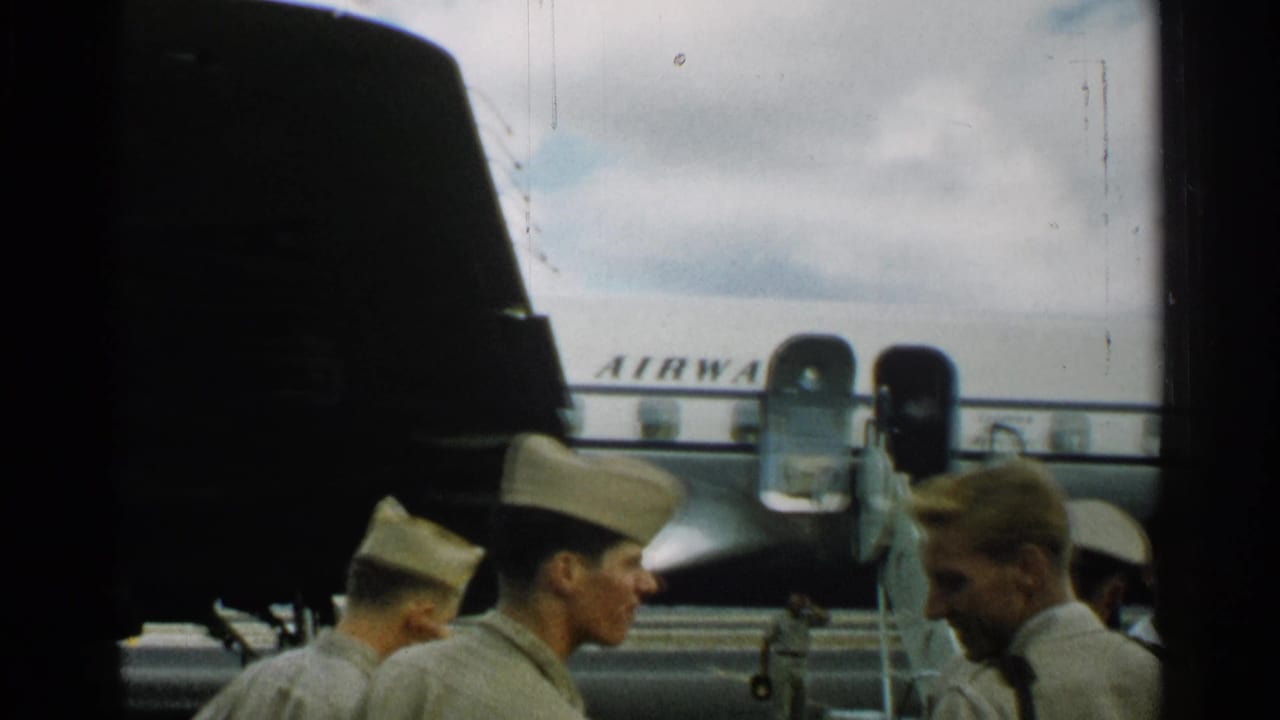 In Japan in 1952, uniformed personnel gather beside a Pan Am passenger aircraft as boarding stairs lead to an open door.