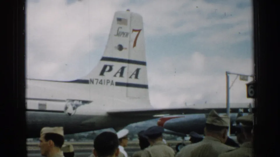 In the closing frame, uniformed men remain on the Japan tarmac near the Pan American aircraft tail, with another aircraft part at right.